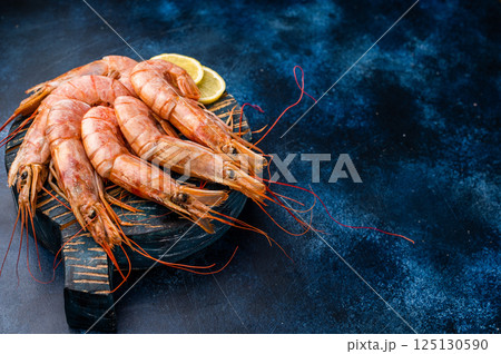 Ready for cooking Red Argentine shrimps, raw Prawns Langostino Austral on wooden board. blue background. top view Ready for cooking Red Argentine shrimps, raw Prawns Langostino Austral on wooden board. blue background. top view 125130590