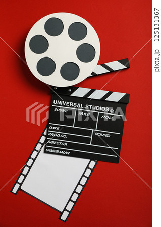 Clapperboard, reel and film on red background, top view Clapperboard, reel and film on red background, top view 125131367