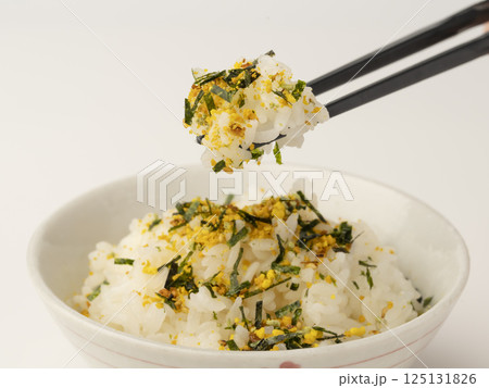 のりたまごふりかけをかけた温かいご飯を箸で持ち上げる 125131826