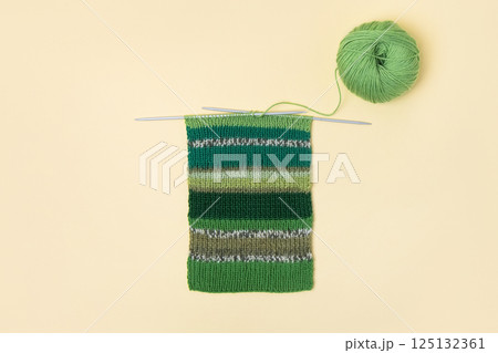 Green knitted wool on table with knitting needles for knitting warm clothes and hobbies needlework 125132361