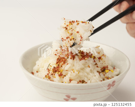 肉そぼろと海苔のふりかけをかけた温かいご飯を箸で持ち上げる 125132455