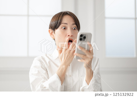スマートフォンを見て驚く女性 125132922