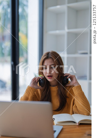 young woman happy, viewing her excellent success score in her e-learning program displayed on her laptop at her desk at home 125133757