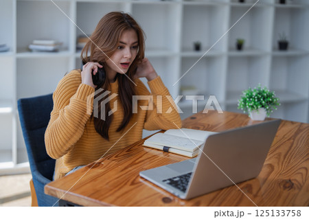 young woman happy, viewing her excellent success score in her e-learning program displayed on her laptop at her desk at home 125133758