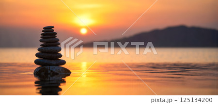 Zen stones stacked in balance on calm water during orange sunset, peaceful lake with soft waves, warm light, serene meditation and nature background Zen stones stacked in balance on calm water during orange sunset, peaceful lake with soft waves, warm light, serene meditation and nature background 125134200