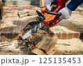 チェーンソーで材木を切断する様子 125135453