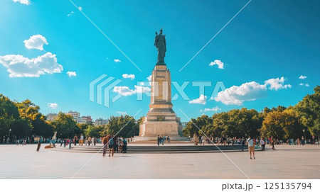 Majestic statue in a sunny city square, surrounded by people enjoying a beautiful day. 125135794