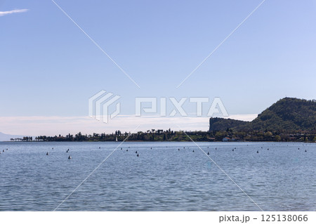 Lake Garda in Italy with clear view of shoreline and prominent silhouette of Rocca di Manerba Lake Garda in Italy with clear view of shoreline and prominent silhouette of Rocca di Manerba 125138066