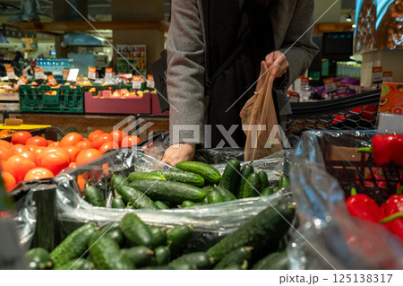 Person Selecting Cucumbers in Grocery Store 125138317