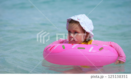 Cute baby girl floating with inflatable ring in the sea Cute baby girl floating with inflatable ring in the sea 125138351