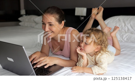 Face of mother lights up with smile looking at laptop screen Face of mother lights up with smile looking at laptop screen 125138417