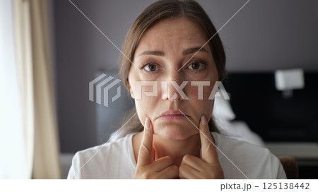 Woman performing facial gymnastics in hotel room Woman performing facial gymnastics in hotel room 125138442