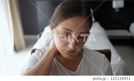 Female remote worker leans back to stretch neck while working Female remote worker leans back to stretch neck while working 125138451