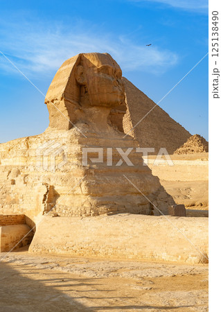 Giant Sphinx stands guard before the Great Pyramid under a clear blue sky in Giza, Egypt during midday 125138490