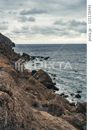 Rugged coastal landscape with rocky shoreline and moody sky near the ocean 125138491