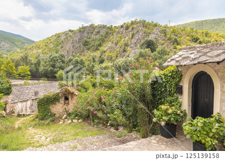 Old stone house in Blagaj village in Bosnia and Herzegovina, Europe. Stone buildings nestled in nature, with a rocky hillside backdrop. The scene is peaceful, blending architecture with environment. Old stone house in Blagaj village in Bosnia and Herzegovina, Europe. Stone buildings nestled in nature, with a rocky hillside backdrop. The scene is peaceful, blending architecture with environment. 125139158