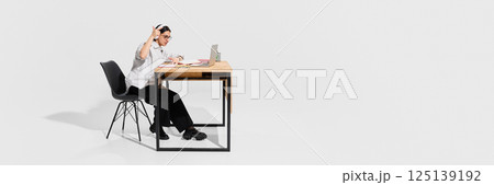 Serious woman in headphones raising finger while discussing academic topic during video call at desk. 125139192