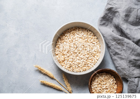 Oat flakes in bowl  with napkin and wheat on grey textured background. 125139675