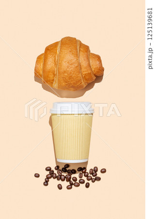 Paper cup with scattered coffee beans and fresh croissant on yellow isolated background with shadow. 125139681