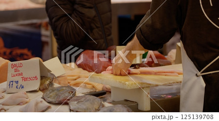 Fishmonger preparing fresh fish fillet on cutting board in seafood market 125139708