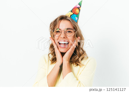 A woman wearing a party hat and glasses is smiling and making a silly face 125141127
