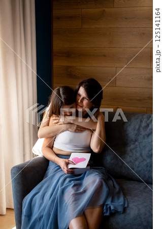 Happy mother's day. Preteen daughter hugs and congratulates moms giving her gift box. Motherhood concept. Happy mother's day. Preteen daughter hugs and congratulates moms giving her gift box. Motherhood concept. 125141164