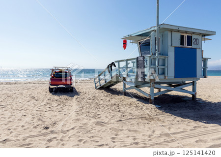 Classic lifeguard tower paired with a rescue vehicle parked nearby on a sandy beach 125141420