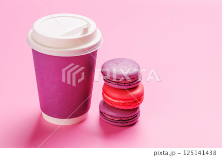 A vibrant arrangement of colorful macarons paired with a paper coffee cup 125141438