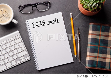 Elegant leather desk setup with laptop, coffee, stationery, and a notepad labeled 2025 Goals 125141488