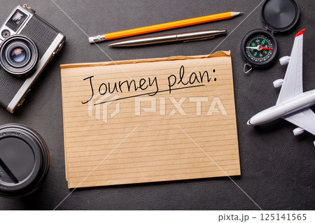 Creative flat lay of a travel-themed desk with notepad for plans 125141565