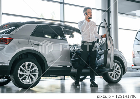 Walking out of automobile. Young man in white clothes is in the car dealership Walking out of automobile. Young man in white clothes is in the car dealership 125141786