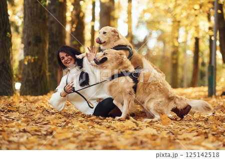 Smiling and playing. Woman on the walk with her two dogs in the autumn forest Smiling and playing. Woman on the walk with her two dogs in the autumn forest 125142518