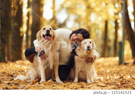 Sitting and smiling. Woman on the walk with her two dogs in the autumn forest 125142525