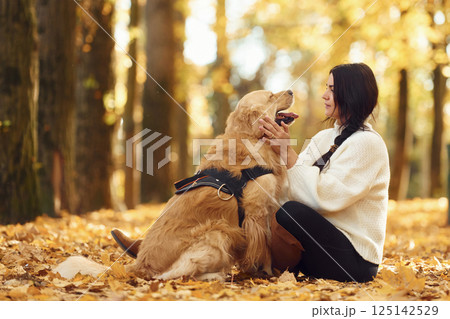 Woman is on the walk with her dog in the autumn forest at daytime Woman is on the walk with her dog in the autumn forest at daytime 125142529