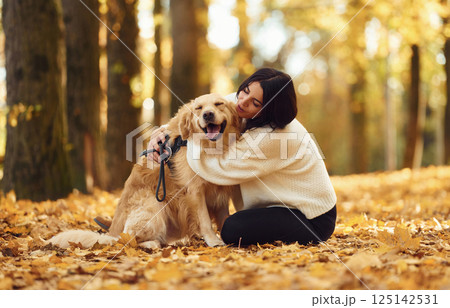 Embracing the animal. Woman is on the walk with her dog in the autumn forest at daytime Embracing the animal. Woman is on the walk with her dog in the autumn forest at daytime 125142531