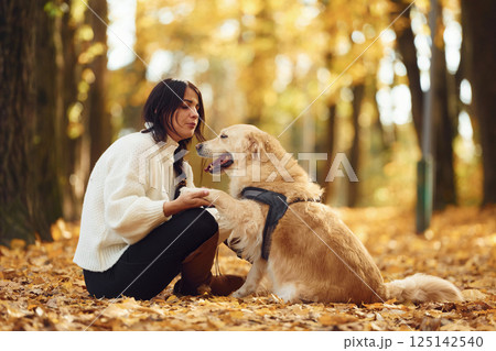 Having fun together. Woman is on the walk with her dog in the autumn forest at daytime 125142540