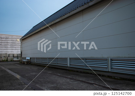 夕暮れのシンプルな建物の裏にベンチが置いてある 125142700