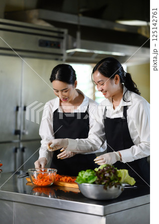 Smiling culinary students preparing vegetables during cooking class 125142761