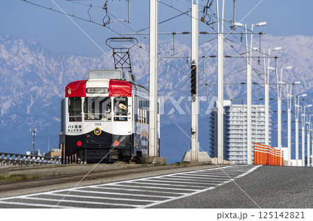 立山連峰を背景に富山大橋を渡る富山地方鉄道のパト電車 125142821