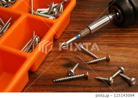 Red screw box and screwdriver on the table. Fitter's place of work. 125143094