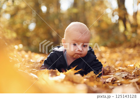 Cute little baby is lying down on the ground with fallen leaves on it Cute little baby is lying down on the ground with fallen leaves on it 125143128