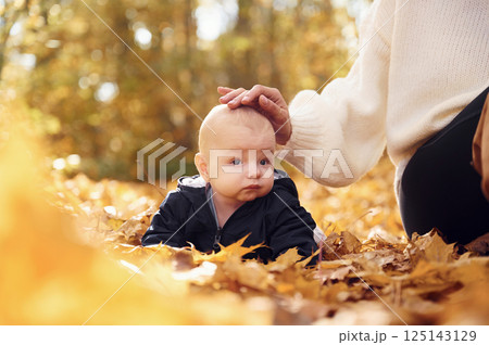Mother with her little baby son is sitting in the forest Mother with her little baby son is sitting in the forest 125143129