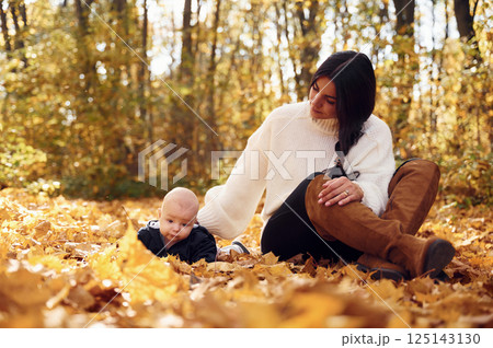 Mother with her little baby son is sitting in the forest Mother with her little baby son is sitting in the forest 125143130