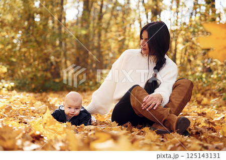 Mother with her little baby son is sitting in the forest 125143131