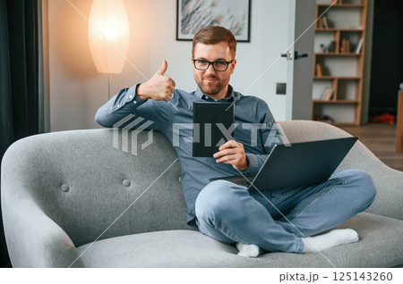 With graphic tablet. Male freelance worker is using laptop at home. Cozy apartment With graphic tablet. Male freelance worker is using laptop at home. Cozy apartment 125143260
