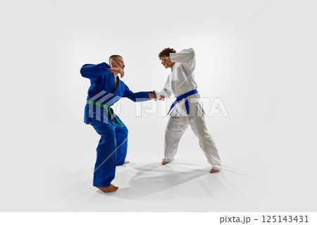 Two fighters engage in active stance, preparing for grip and counter, capturing anticipation, focus, and readiness essential in martial arts competition. 125143431
