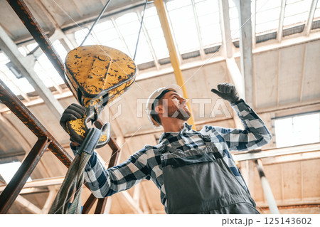 Working with crane. Man in a factory in uniform is indoors 125143602