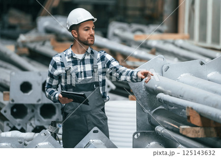 With graphic tablet. Factory male worker in uniform is indoors With graphic tablet. Factory male worker in uniform is indoors 125143632