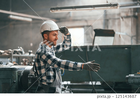 Friendly factory male worker in uniform is indoors giving hand Friendly factory male worker in uniform is indoors giving hand 125143687