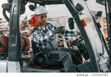 Driving the vehicle. Factory male worker in uniform is indoors Driving the vehicle. Factory male worker in uniform is indoors 125143761